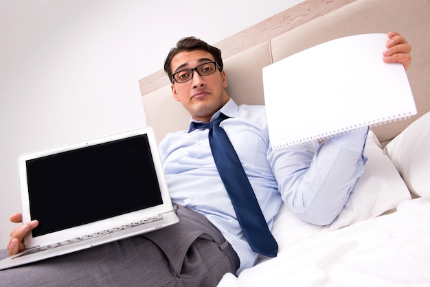 Businessman working in the bed at home