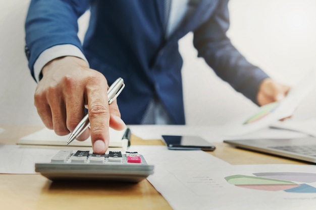 Businessman working on desk and using calculator in office