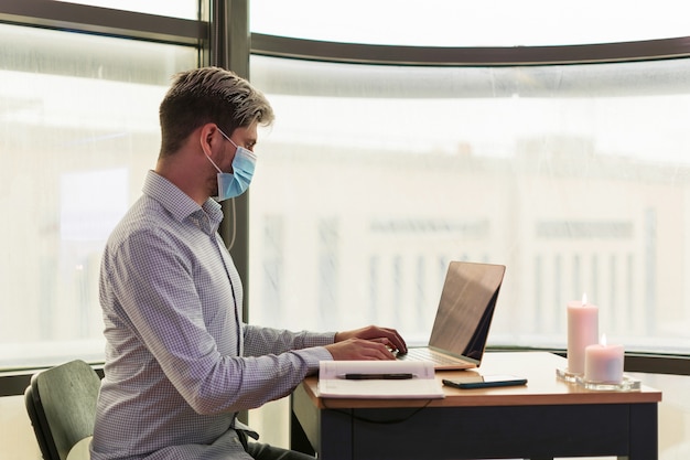 Foto uomo d'affari che lavora nel suo ufficio, con la mascherina sanitaria per prevenire il virus covid.