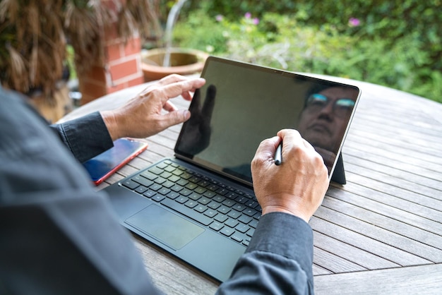 庭に面したパティオでタブレットに取り組むビジネスマンの接写