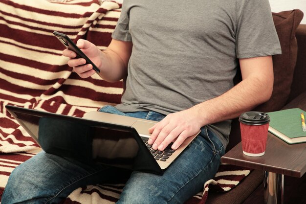 Businessman working at home with a laptop on sofa Top view