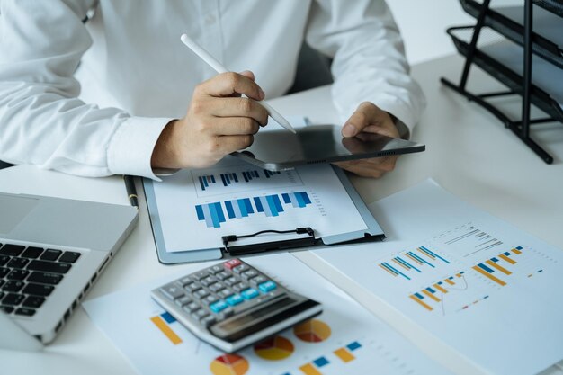 Businessman working at home with tablet and laptop computer and papers on desk