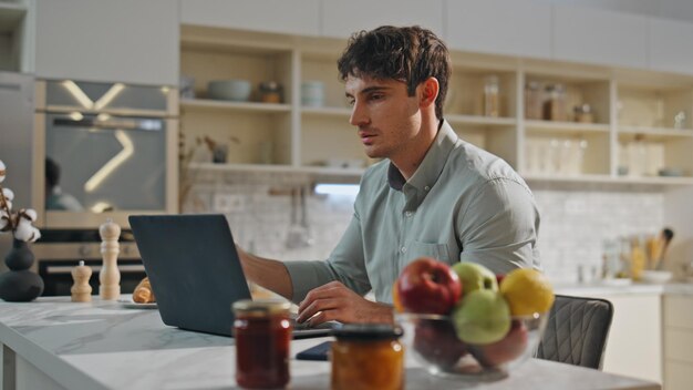 オンラインで勉強する学生をクローズアップするラップトップを持つキッチンテーブルで働くビジネスマン