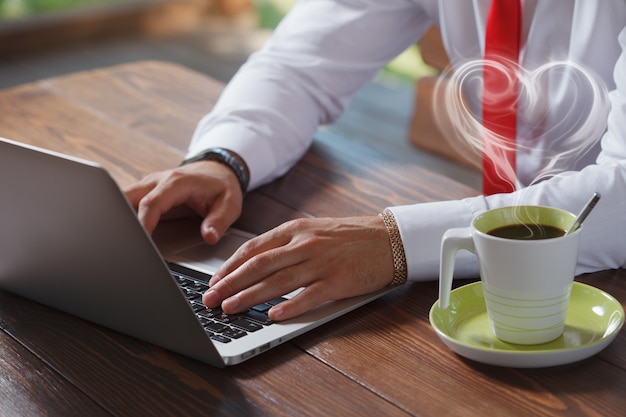 Businessman working on laptop in cafe and drinking coffee