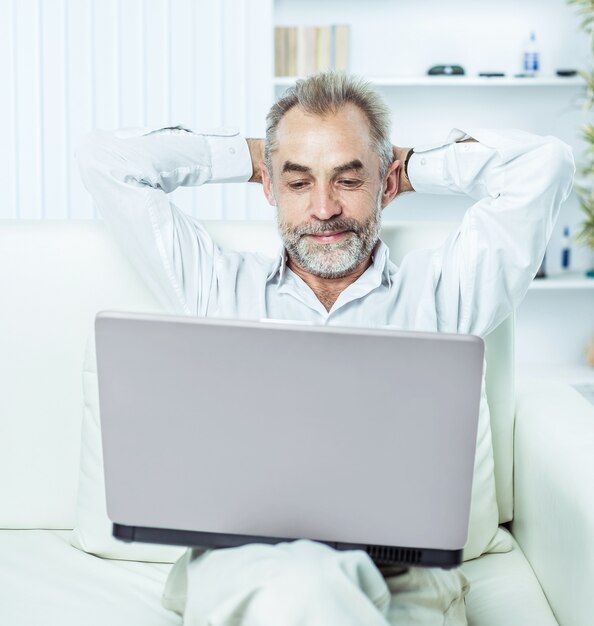 Businessman working on laptop sitting on sofa in modern office.