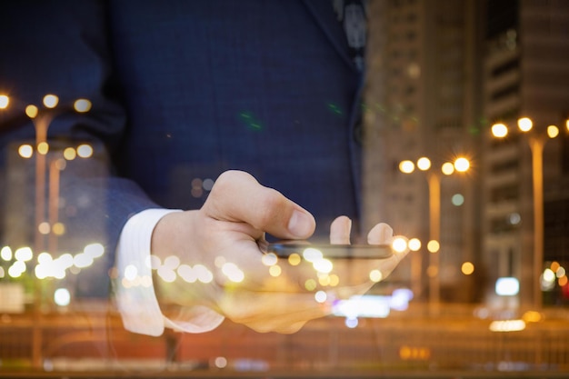 Businessman working in the mobile on the background of night city