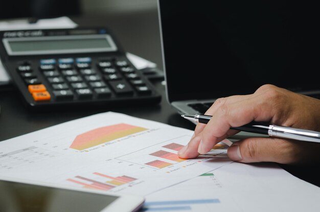 Businessman working in an office with a laptop with data documents graphs and charts marketing research statistics and financial development