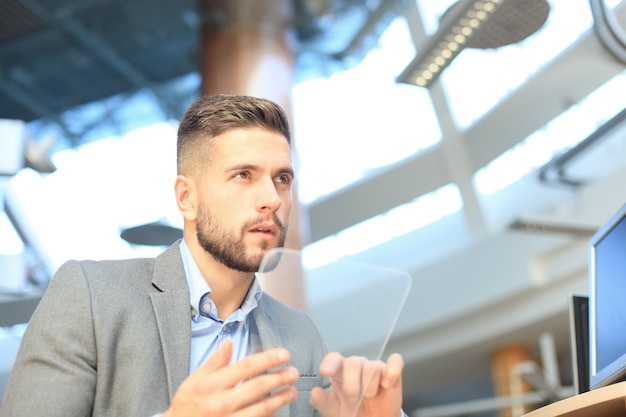 Businessman working in office with transparent tablet and laptop.