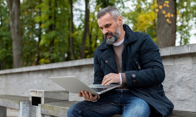 Businessman working online on laptop in city park