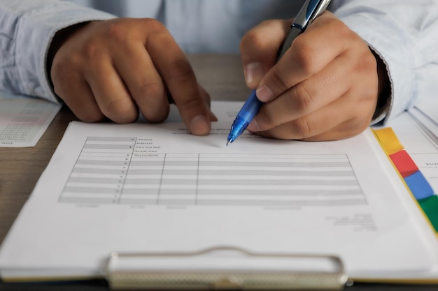 Businessman working reading documents signing contract on paper business document working on laptop computer on desk close up