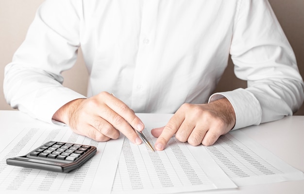 Photo businessman working at table with pen and calculator on white background.