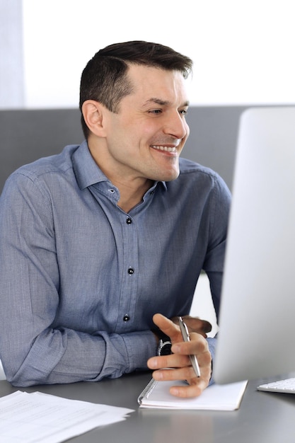 Businessman working with computer in modern office. Headshot of male entrepreneur or company director at workplace. Business concept.