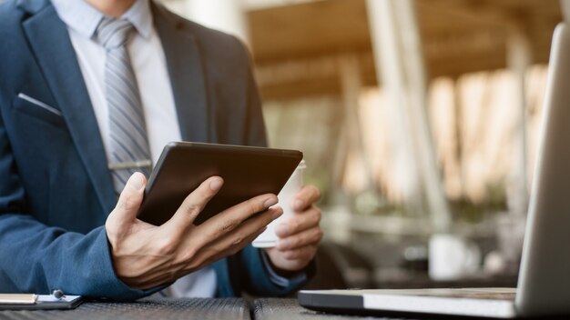 Uomo d'affari che lavora con la tavoletta digitale e il computer portatile con la strategia di affari finanziaria in un caffè del caffè