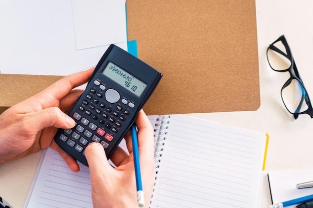 Businessman working with financial report using calculator Top view