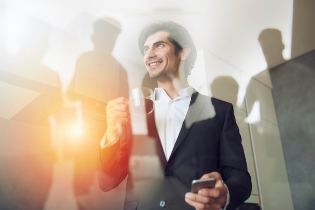 Businessman works with his smartphone in office double exposure