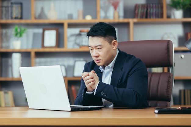 사업에 대해 걱정하는 사업가는 사무실에 앉아 노트북 화면을 초조하게 보고 좌절하고 있다