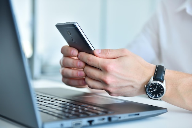 Businessman writes message on smartphone in office