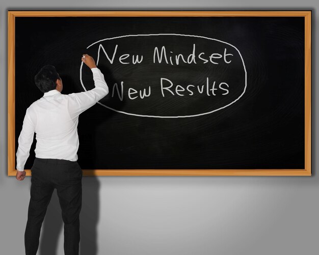 Foto un uomo d'affari che scrive parole di new mindset new results con il gesso su una lavagna davanti a lui