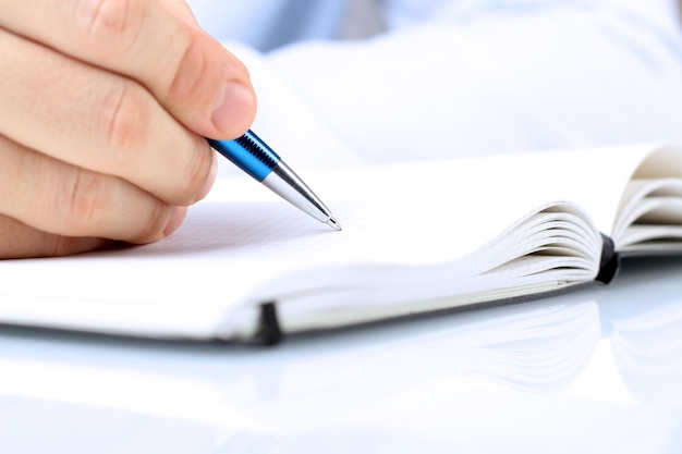 Businessman writing in a notebook while sitting at a his desk