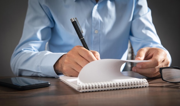 Businessman writing on a notepad in office