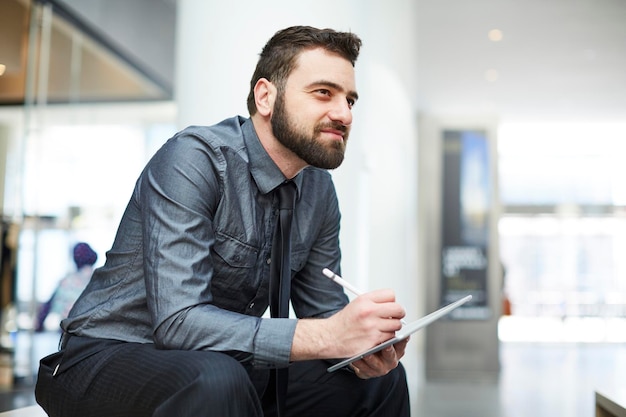 Photo businessman writing notes in diary while sitting at office