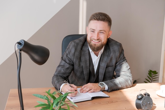 Businessman writing notes while sitting at his desk Young bearded man