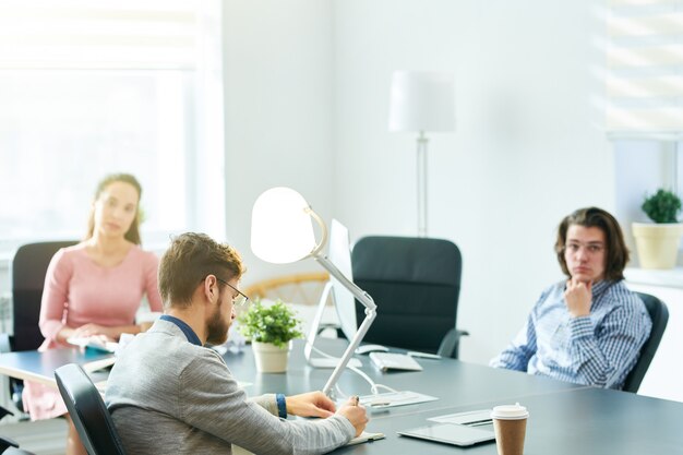 Businessman writing tasks at staff meeting