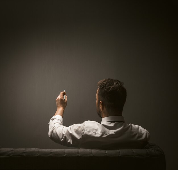 Businessman writing with pen on dark gray wall