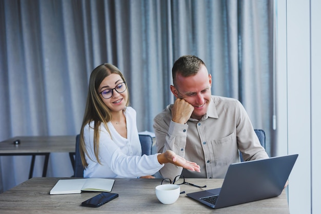 Photo businessmen are discussing while working with laptop in the office focused business people cooperating in a modern workspace two young businessmen are sitting together at a table