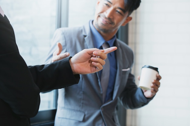 businessmen are examining documents, talking and smiling while standing in office