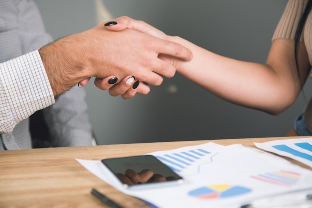 Businessmen in front of a desk shake hands