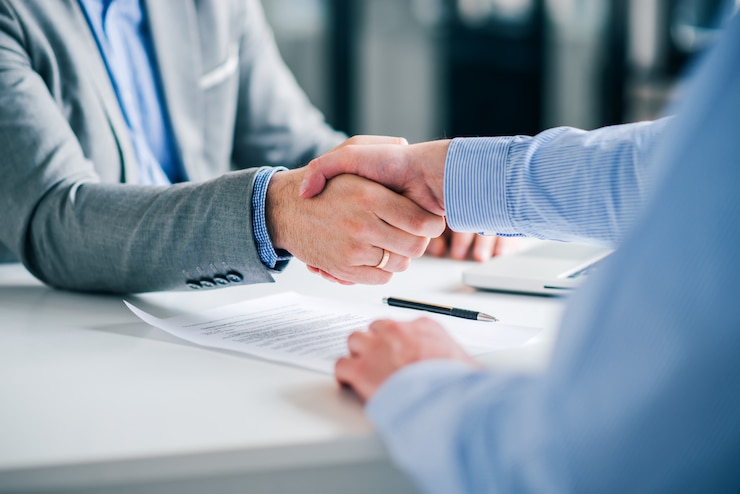 Photo businessmen handshaking over signed contract.