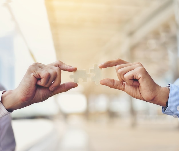 Businessmen hold jigsaw puzzles for each other