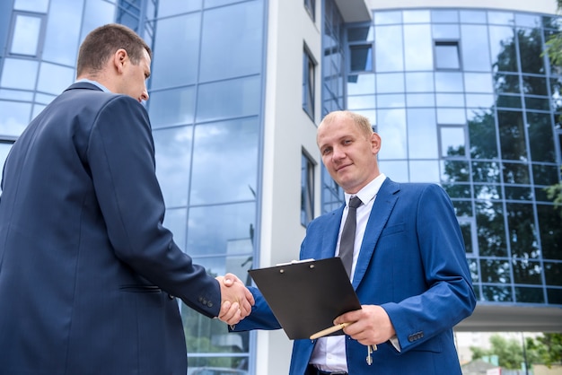 Businessmen making deal and handshaking outside building