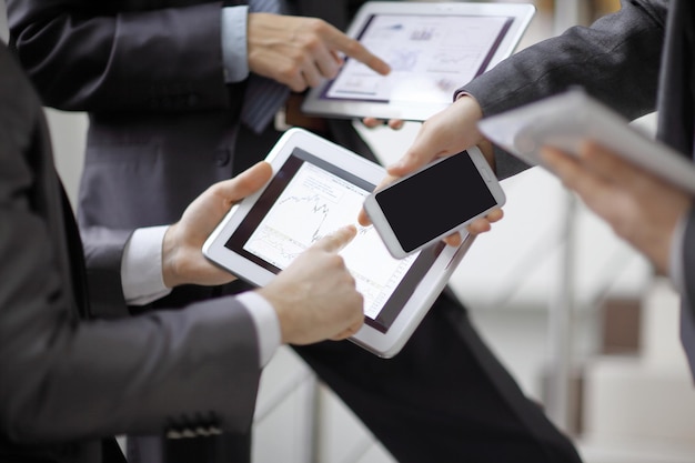 Businessmen at meeting presenting charts on smartphone tablet