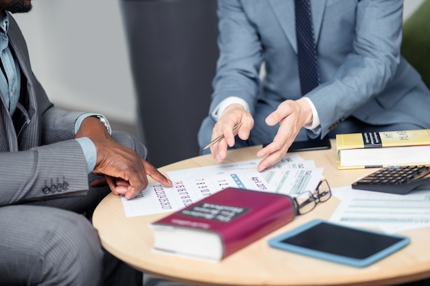 Businessmen near calendar. Two businessmen sitting at the table and discussing next negotiation near calendar