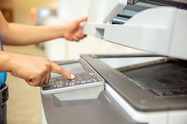 Businessmen press the button on the panel of the copier