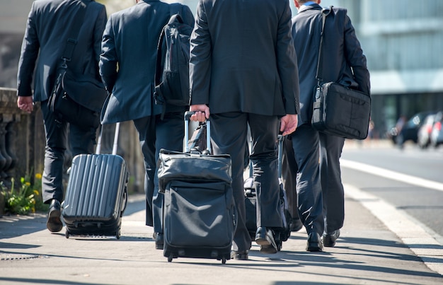 Businessmen pulling suitcases