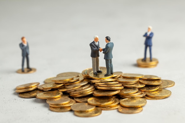 Businessmen shake hands as a successful profitable transaction Businessmen on a stack of gold coins