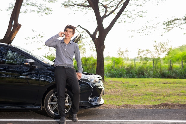 壊れた車のために携帯電話で話しているビジネスマン