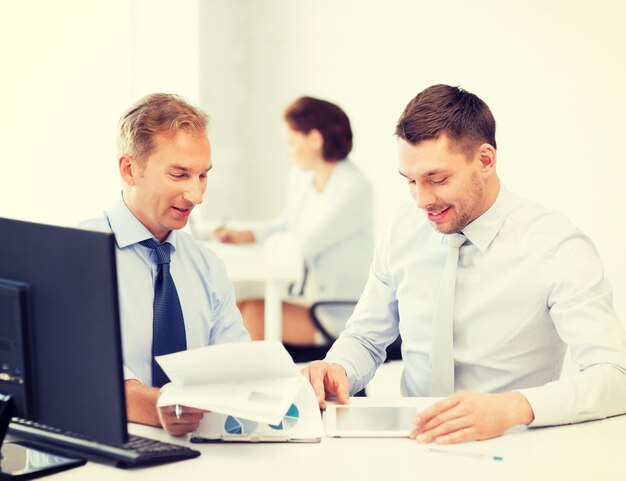 businessmen with notebook and tablet pc discussing graphs on meeting