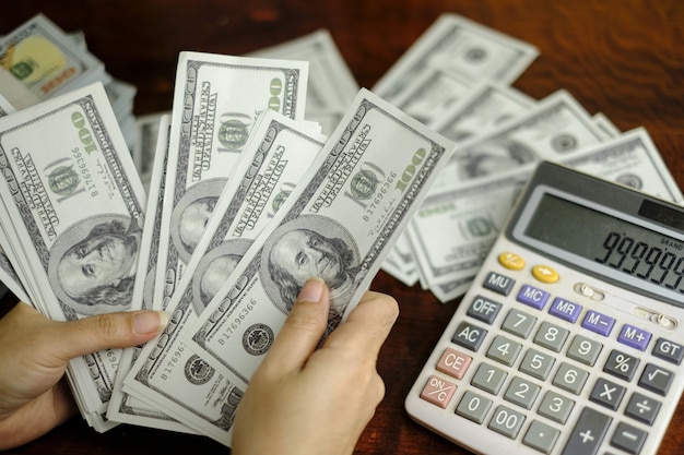 Businessmen women counting money on a stack of 100 US dollars banknotes