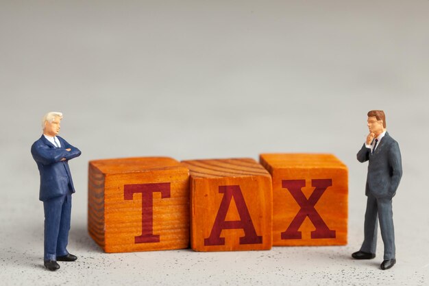 Businessmen and word TAX on gray background.