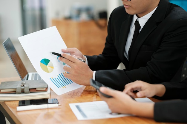 Businessmen working discussing analyzing using laptop and graphs