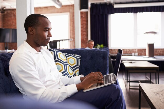 Businessmen Working On Sofas In Relaxation Area Of Office