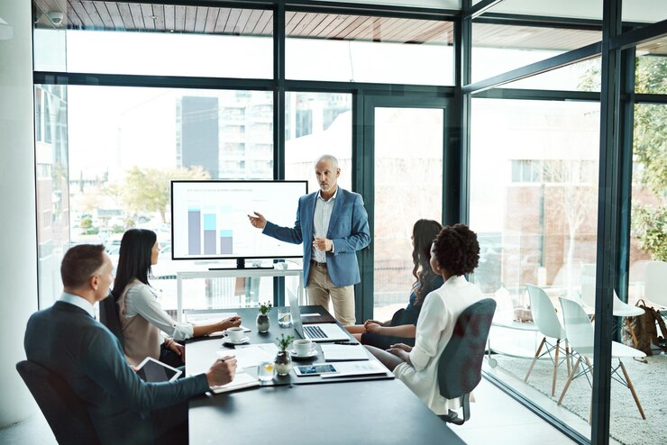 Photo businesspeople attending a presentation in the boardroom about growth innovation and development with graphs in a boardroom mature man showing great leadership while talking about company vision