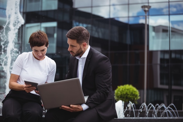 Businesspeople discussing on digital tablet and laptop