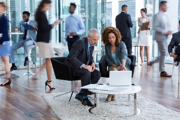 Businesspeople discussing over laptop