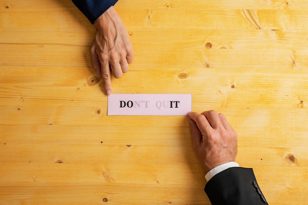 Businesspeople holding a pink paper with a Dont quit sign fading into a Do it message