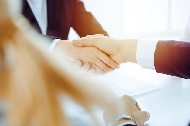 Foto uomini d'affari o avvocati che si stringono la mano finendo la riunione o la negoziazione in un ufficio soleggiato stretta di mano e partnership aziendale